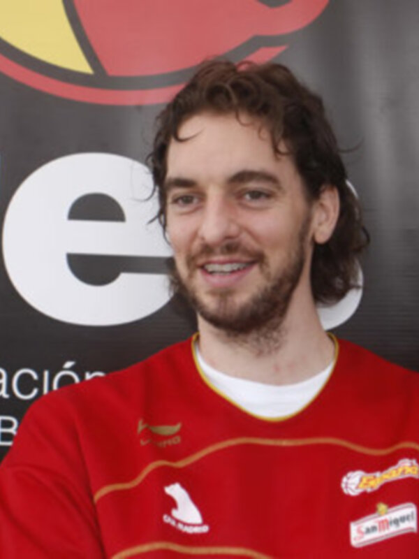 Jugador de baloncesto con camiseta roja y logo de la Federación Española de Baloncesto en el fondo.