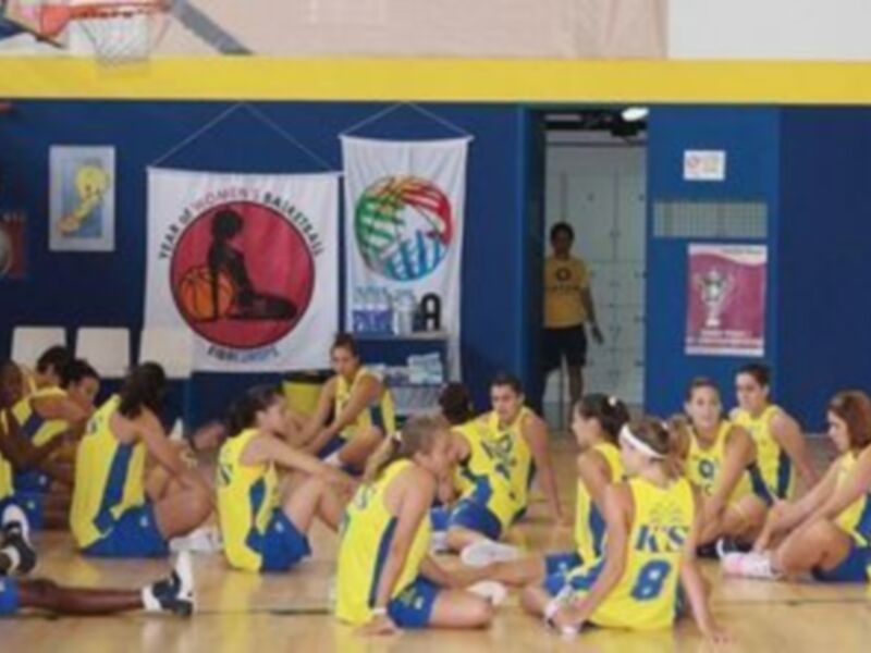 Equipo de baloncesto femenino en una reunión estratégica en el gimnasio.