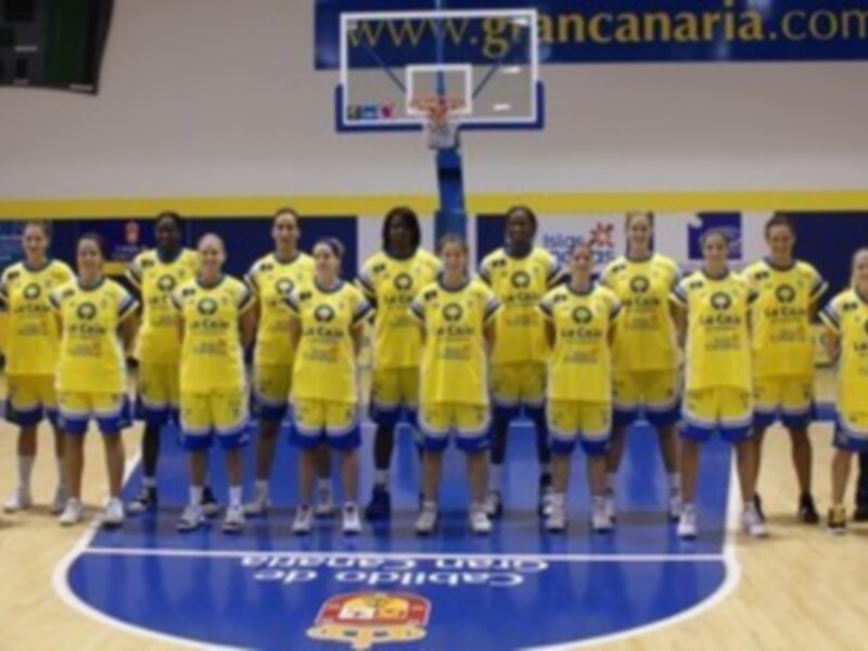 Equipo de baloncesto femenino en uniforme amarillo y azul, posando en una cancha de baloncesto.
