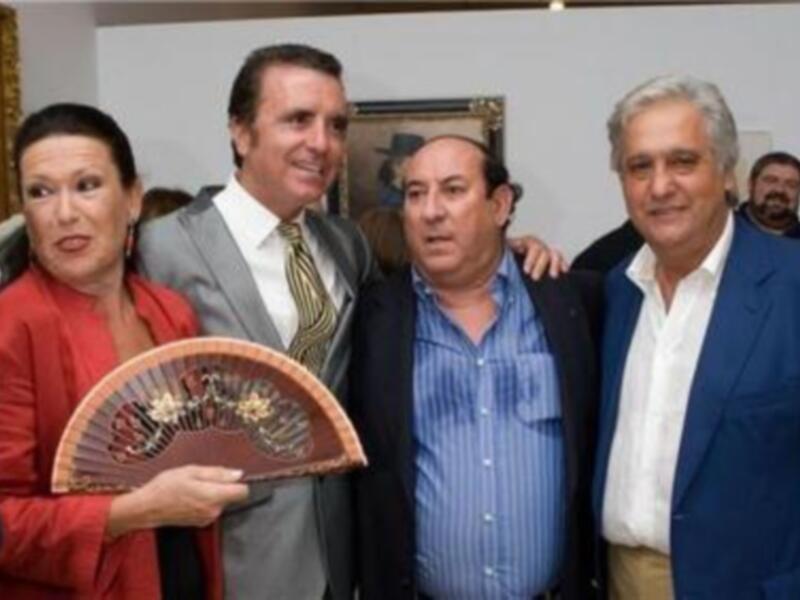 Personas posando juntas en una recepción formal, una de ellas sostiene un abanico de madera.