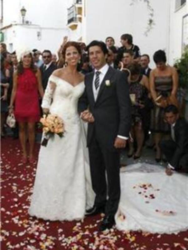 Casamiento en una calle adoquinada con invitados y petalos de flor en el suelo.
