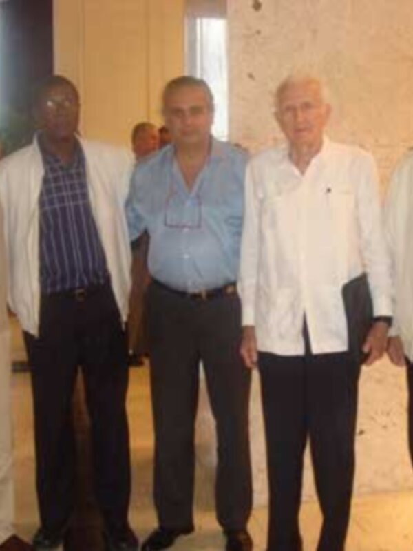 Una reunión de hombres mayores y jóvenes en un entorno formal, posando juntos para una foto.