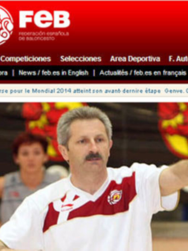 Entrenador de baloncesto en una sesión de entrenamiento, con el logo de la FEB en el fondo.