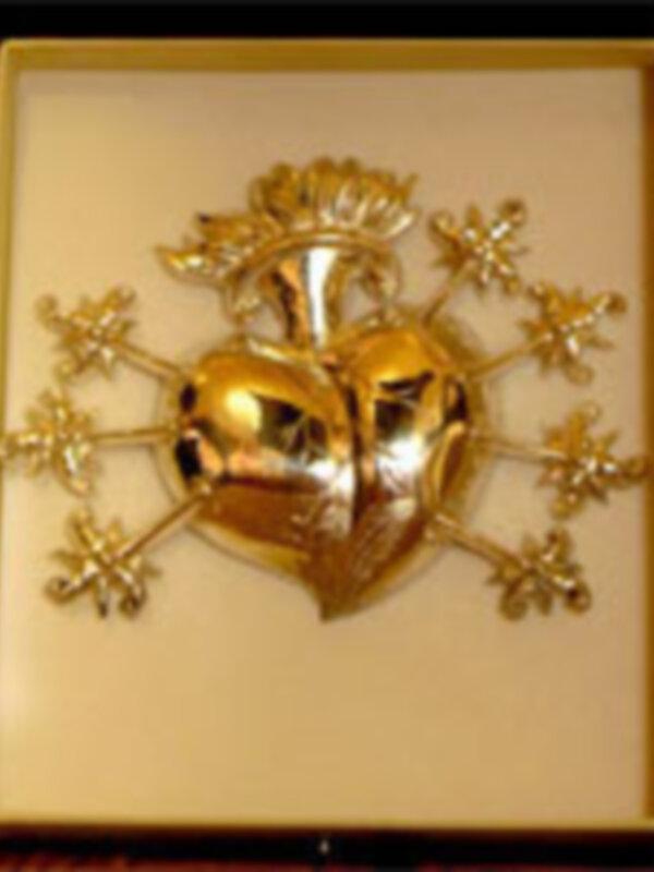 Broche dorado con diseño de corazón y detalles florales en un paquete blanco