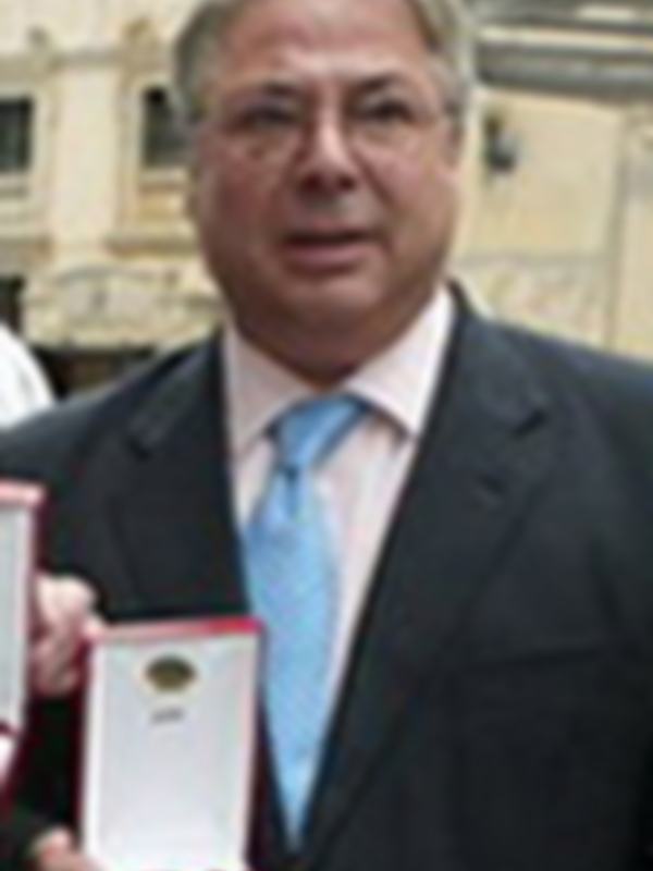Un hombre con una medalla en la mano, posiblemente un premio o reconocimiento.