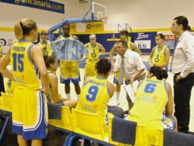 Entrenamiento de baloncesto femenino con equipo en uniforme amarillo y azul, en un gimnasio.