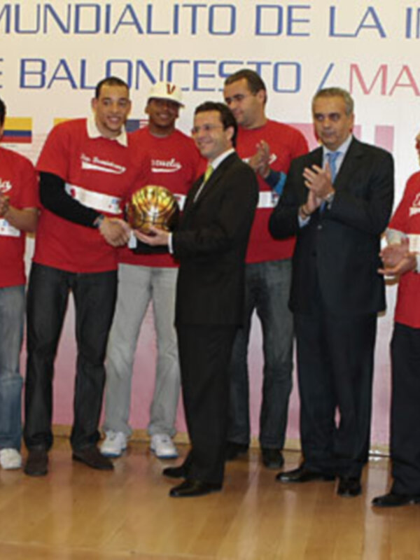 Equipo de baloncesto celebrando con trofeo en el gimnasio de la institución educativa.