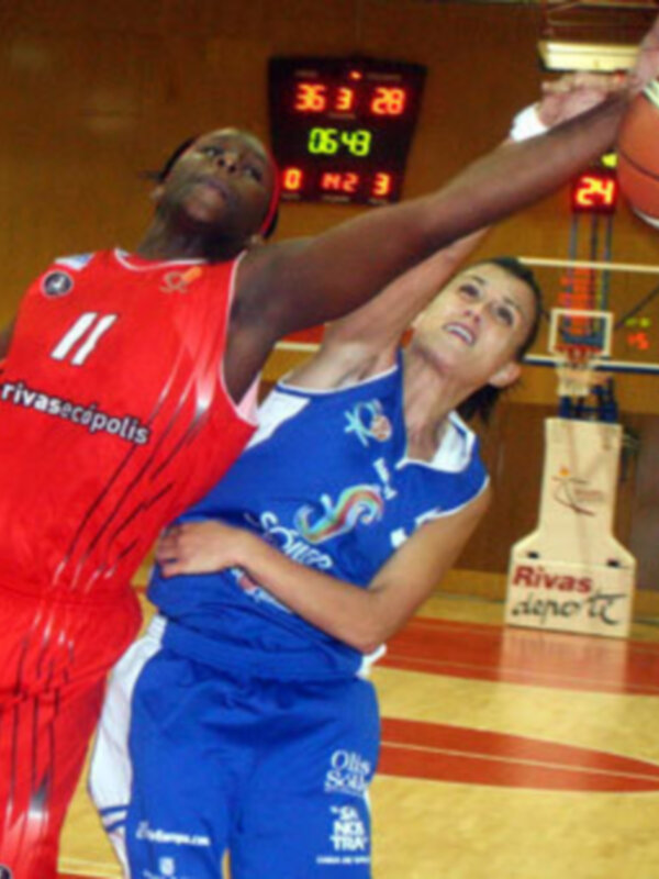 Jugadores en acción durante un partido de baloncesto, uno en rojo y otro en azul, luchando por el balón en el aro.