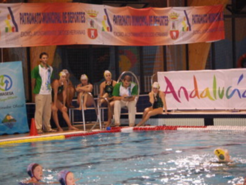 Competición de waterpolo en piscina, con banderas y pancartas de Andalucía y el Patrocinio Municipal de Benalmádena.