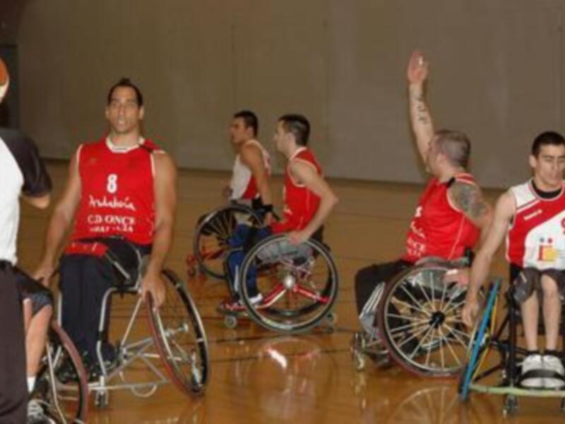 Equipo de baloncesto en silla de ruedas celebrando un punto durante un partido de baloncesto en silla de ruedas.
