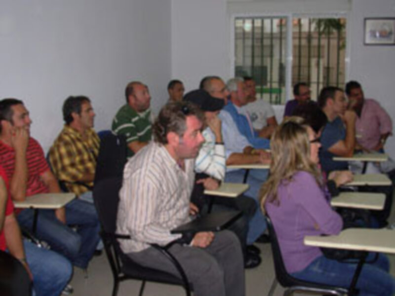 Grupo de personas sentadas en una sala de conferencias o reunión, participando en una discusión o escuchando una presentación.