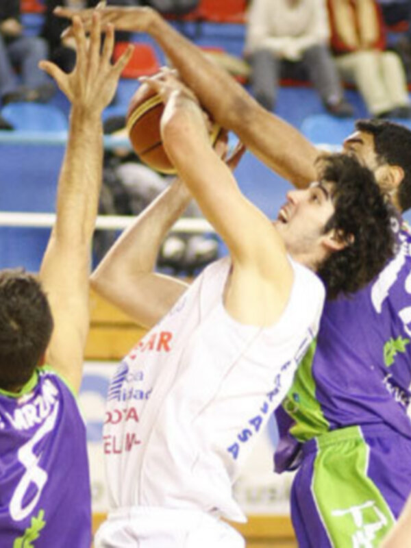 Intensa acción de baloncesto durante un partido, jugadores en plena disputa por el balón.