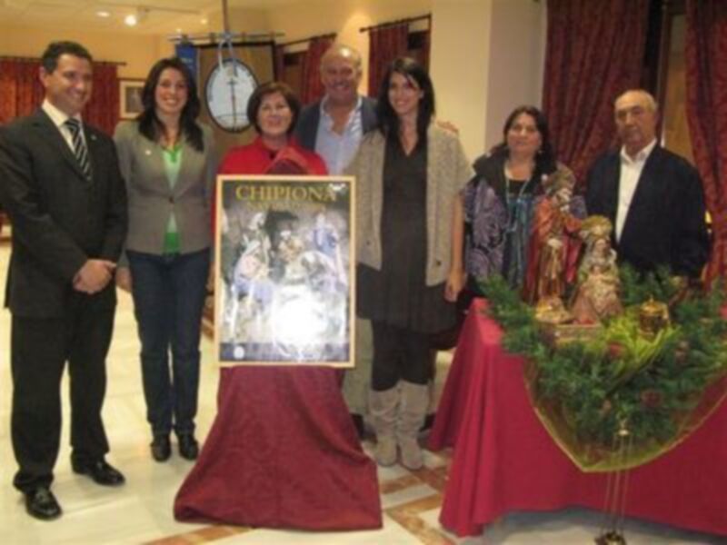 Una familia posa junto a una imagen de la Virgen María y el Niño Jesús en una celebración navideña.