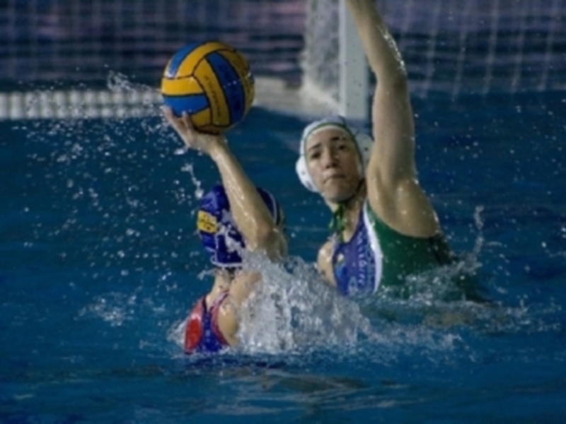 Jugadora de waterpolo en acción, lanzando el balón con precisión en el agua.