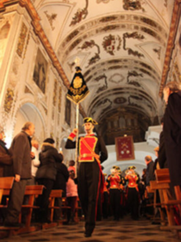 Guardia de honor en una ceremonia religiosa en una iglesia histórica con techos ornamentados y piso de mosaico.