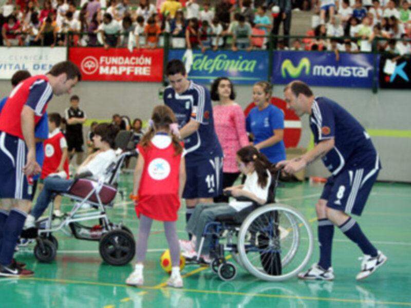 Una escena deportiva con personas en sillas de ruedas y camisetas deportivas, posiblemente durante un partido o evento.