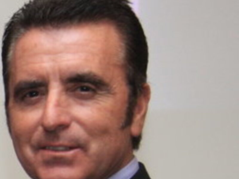 Elegante hombre con peinado moderno y camisa azul clásica, posando con una expresión seria.