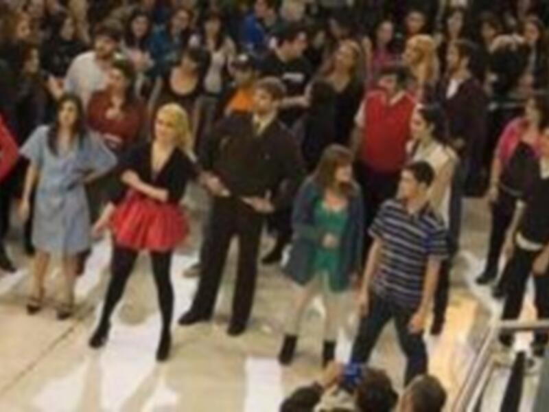 Una multitud de personas en un evento social, posando y disfrutando de la noche. La escena está iluminada con luces brillantes, destacando a los individuos en el centro de la imagen.
