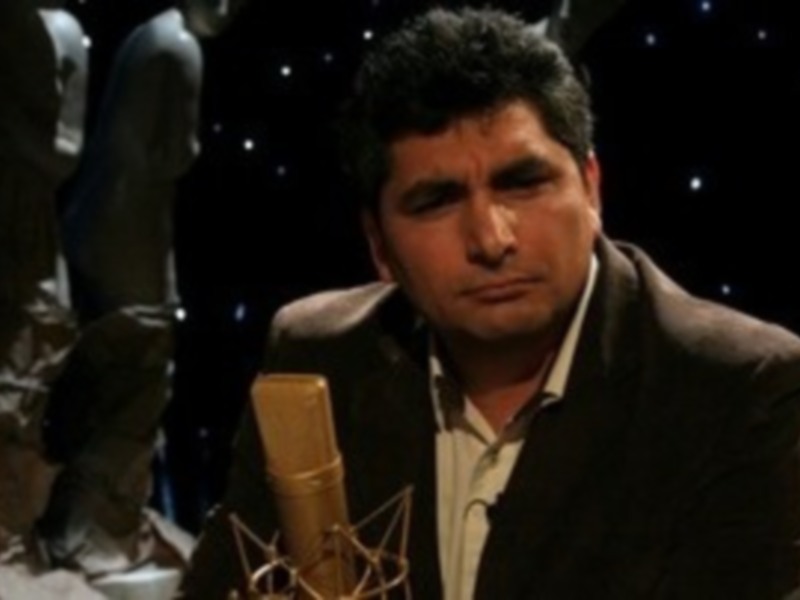 Persona en estudio de grabación con micrófono y estatuas al fondo