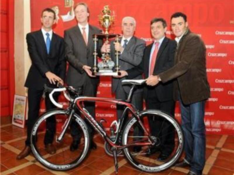 Celebración de un evento deportivo con una bicicleta de carreras y un trofeo en el centro.