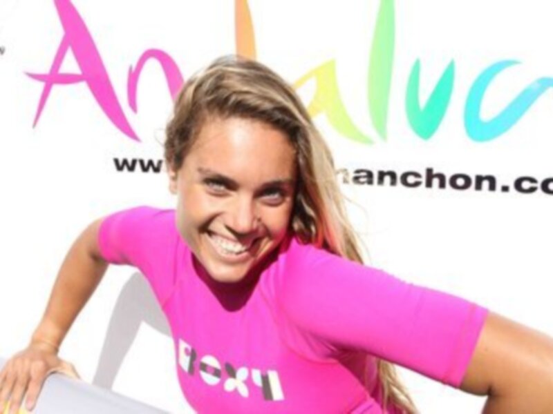 Retrato de una mujer sonriente en traje de baño rosa con el logo de 'Anchon' en el fondo.