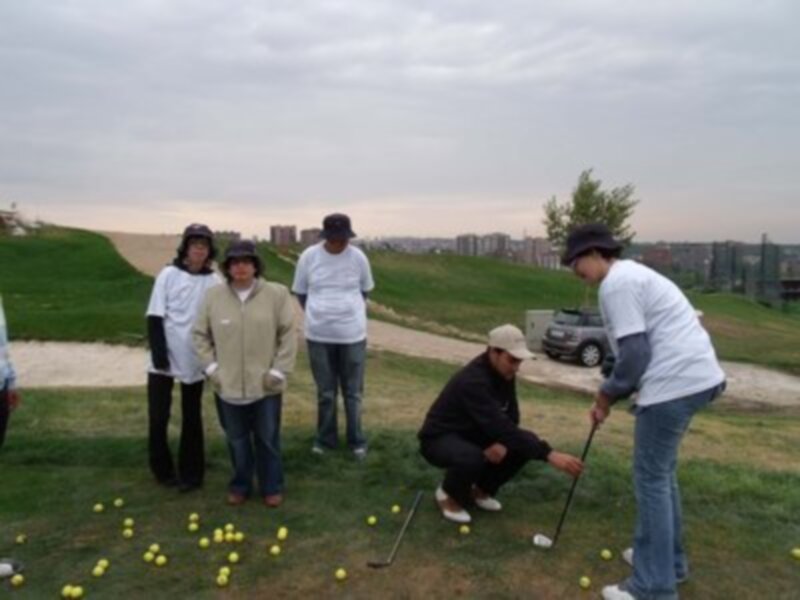 Un grupo de personas aprende a jugar golf en un campo al atardecer.