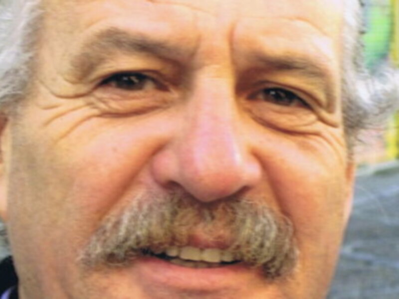 Retrato de hombre con barba y cabello gris, sonriendo.