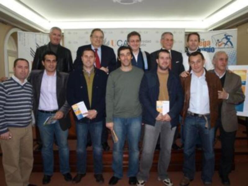 Gruppo di uomini in una conferenza stampa o evento ufficiale, con cartelloni sullo sfondo.