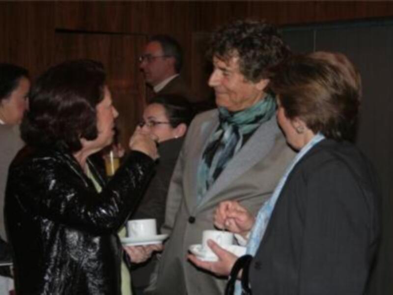 Un grupo de personas disfrutando de una reunión social, con una mujer en el centro sonriendo y conversando con otros invitados. La escena transmite un ambiente de amistad y convivencia.