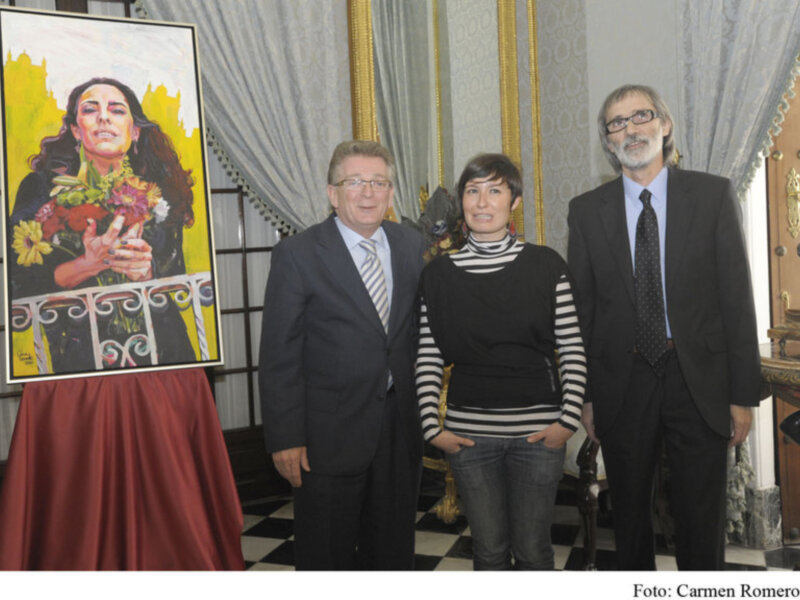 Presentación de un retrato artístico en un evento formal con tres personas posando junto a la obra.