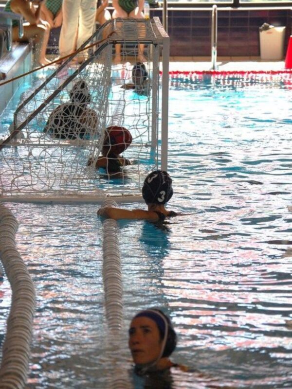 Jugadores de waterpolo en acción durante un partido en una piscina.