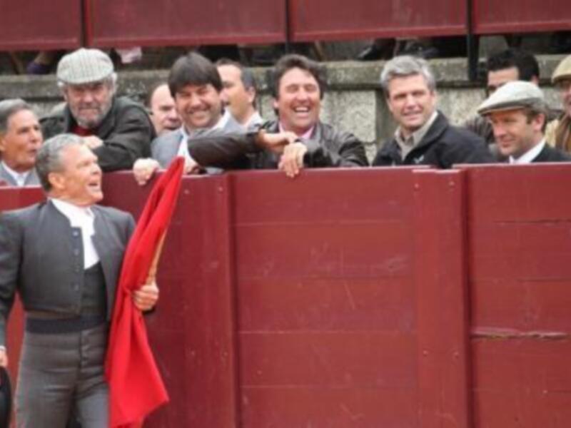 Un torero con capa roja y público en una plaza de toros durante una corrida de toros.