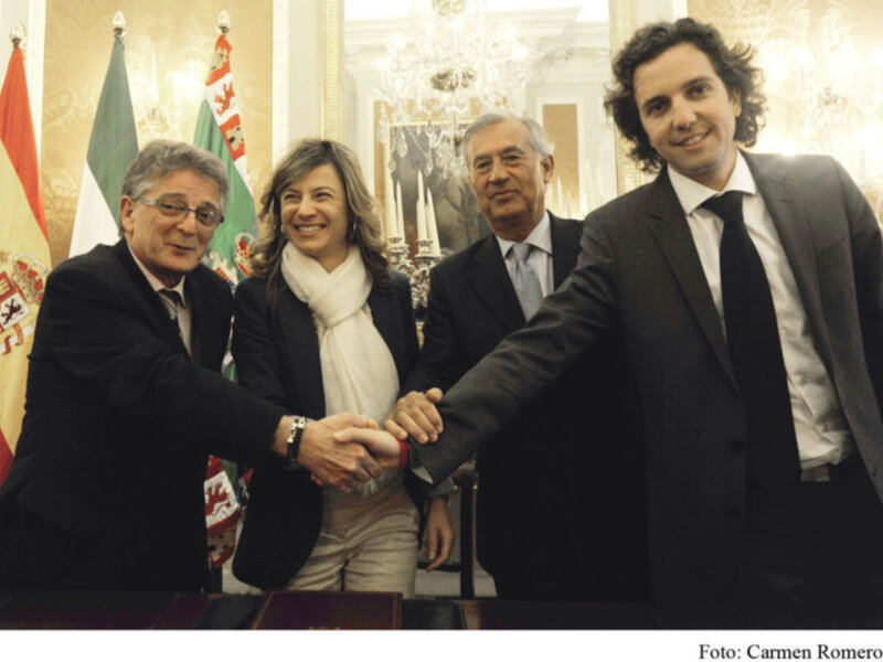 Ceremonia de firmas entre autoridades en un ambiente formal con banderas y decoración oficial.