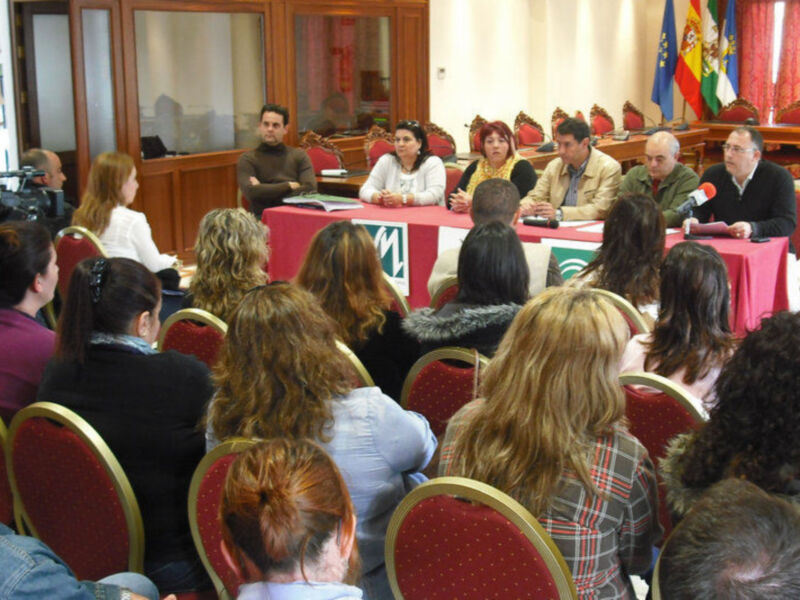 Reunión de trabajo en una sala de conferencias con participantes sentados alrededor de una mesa.