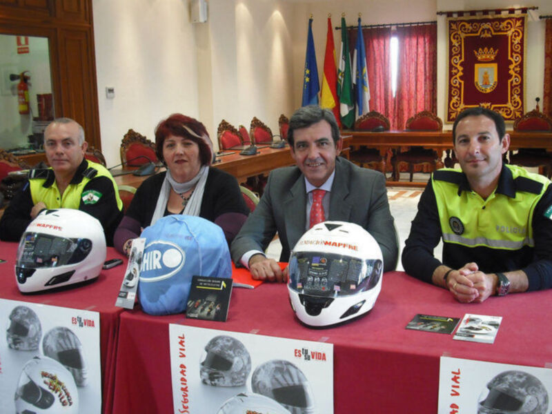 Presentación de cascos de seguridad vial en un evento oficial con autoridades y representantes de seguridad.