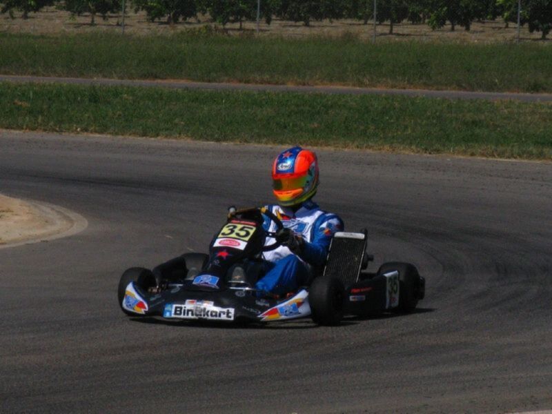 Competidor en karting en una curva de circuito al aire libre.