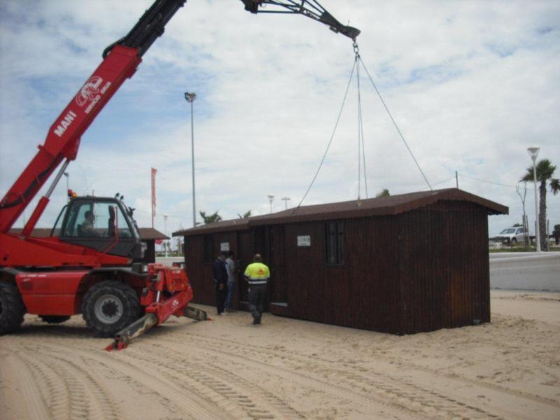 Traslado de una estructura móvil con un grúa sobre una playa.