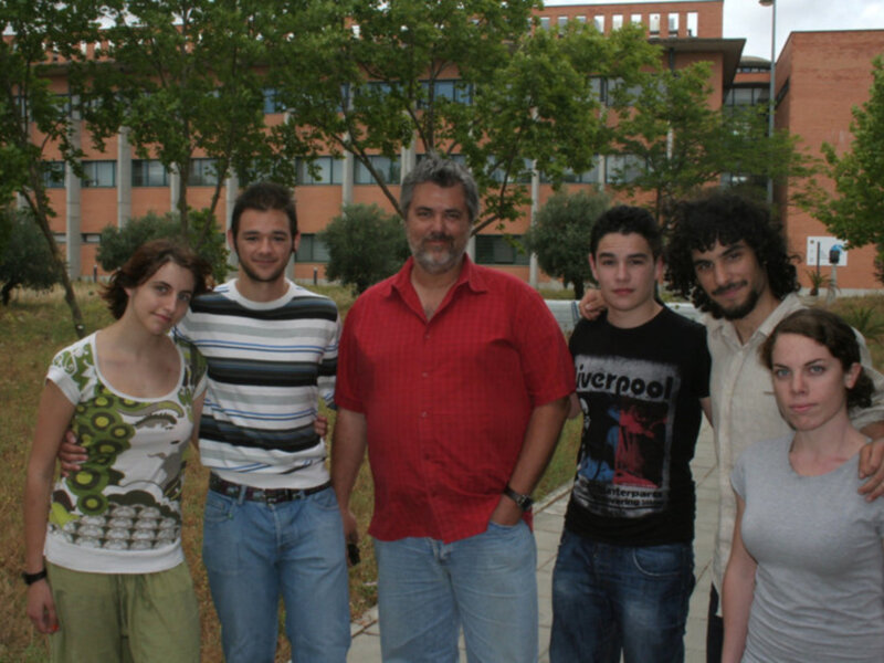 Una familia de cinco personas posa juntos en un parque, con un edificio en el fondo.