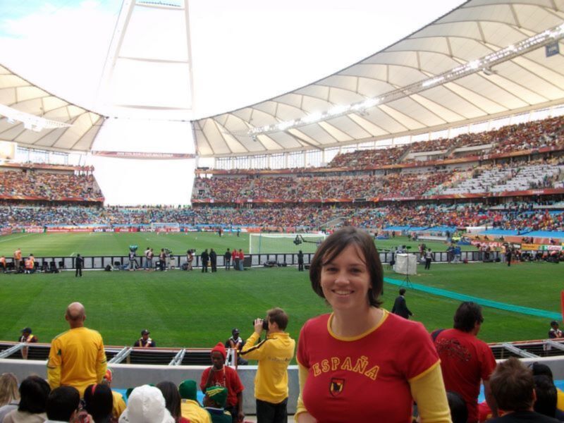Una persona con camiseta de España en el Estadio Nacional, durante un evento deportivo. El estadio está lleno de espectadores y el cielo está parcialmente nublado.
