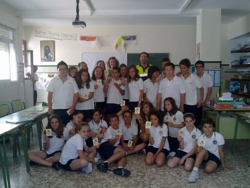 Grupo de estudiantes en una escuela posando con tarjetas en un aula.