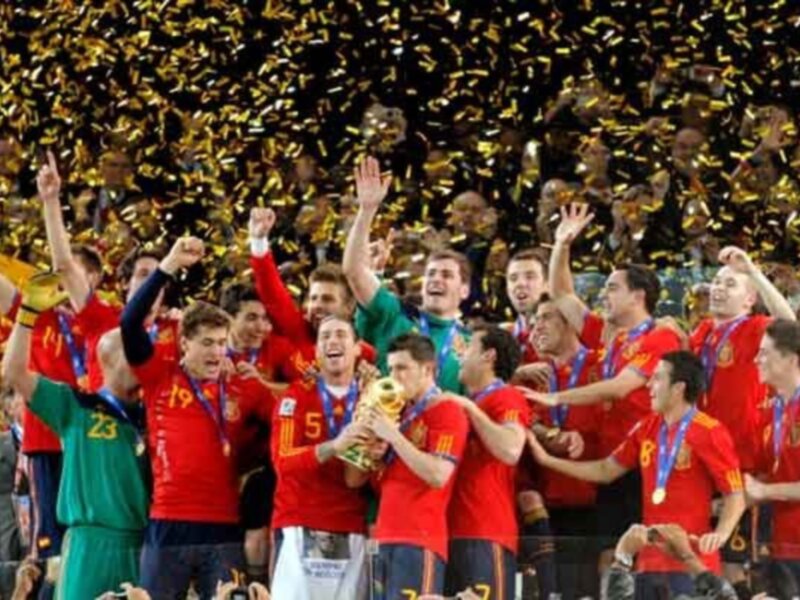 Equipo de fútbol celebrando con el trofeo y confeti dorado tras una victoria.