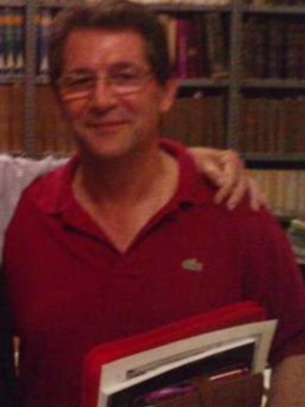 Persona con camiseta roja sosteniendo un libro, en un entorno con estanterías de libros.
