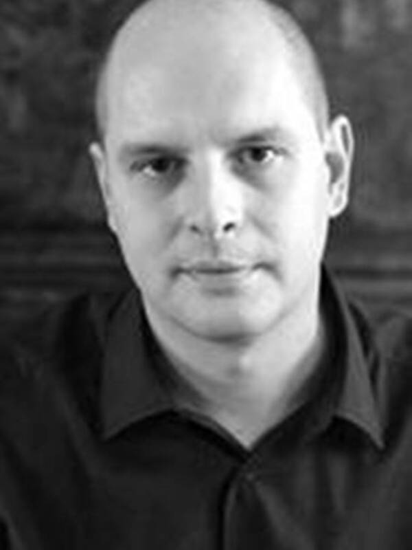 Retrato en blanco y negro de un hombre con camisa negra, fondo oscuro