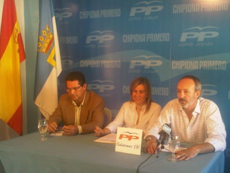 Tres personas sentadas en una mesa con un cartel que dice 'Soluciones Ya!' en una conferencia de prensa.