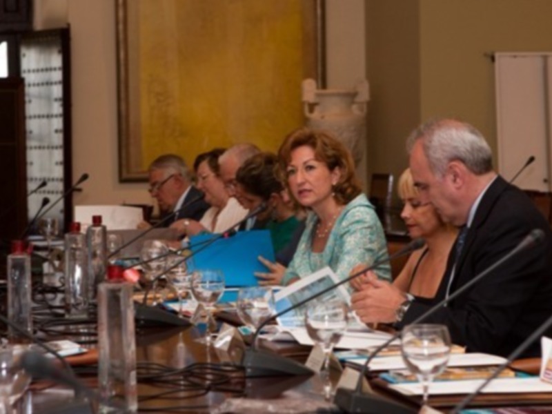 Reunión de trabajo en una sala formal con participantes discutiendo y tomando notas.