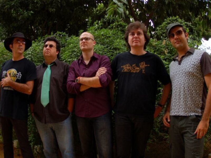 Un grupo de músicos posando juntos en un entorno natural, posiblemente antes de un concierto o en una sesión de fotos promocionales.