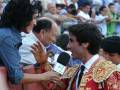Un torero en traje tradicional habla con una periodista durante un evento deportivo.