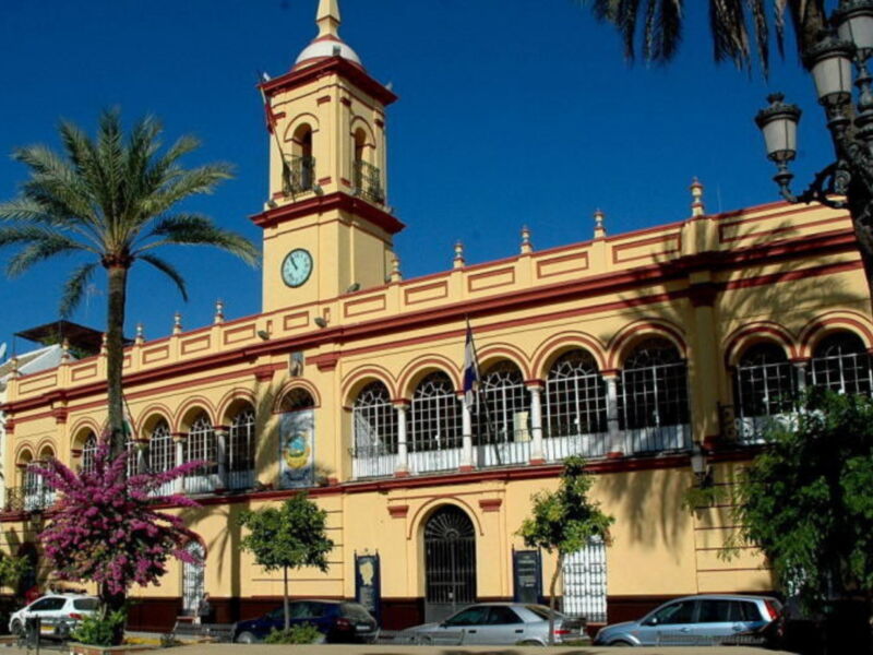 Edificio histórico amarillo con reloj y detalles arquitectónicos en Málaga, España.