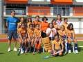 Una escuela de hockey infantil con niños y niñas en uniformes amarillos, posando frente a una cancha de hockey.