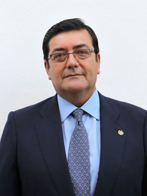 Elegante retrato de un hombre en traje con corbata y broche dorado en el pecho.